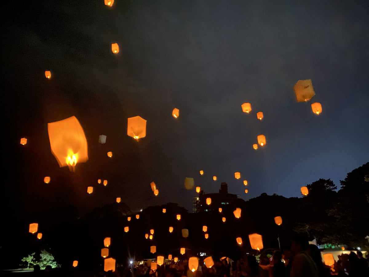 オレンジ色のスカイランタンが桂浜の夜空にいっせいに上がる様子